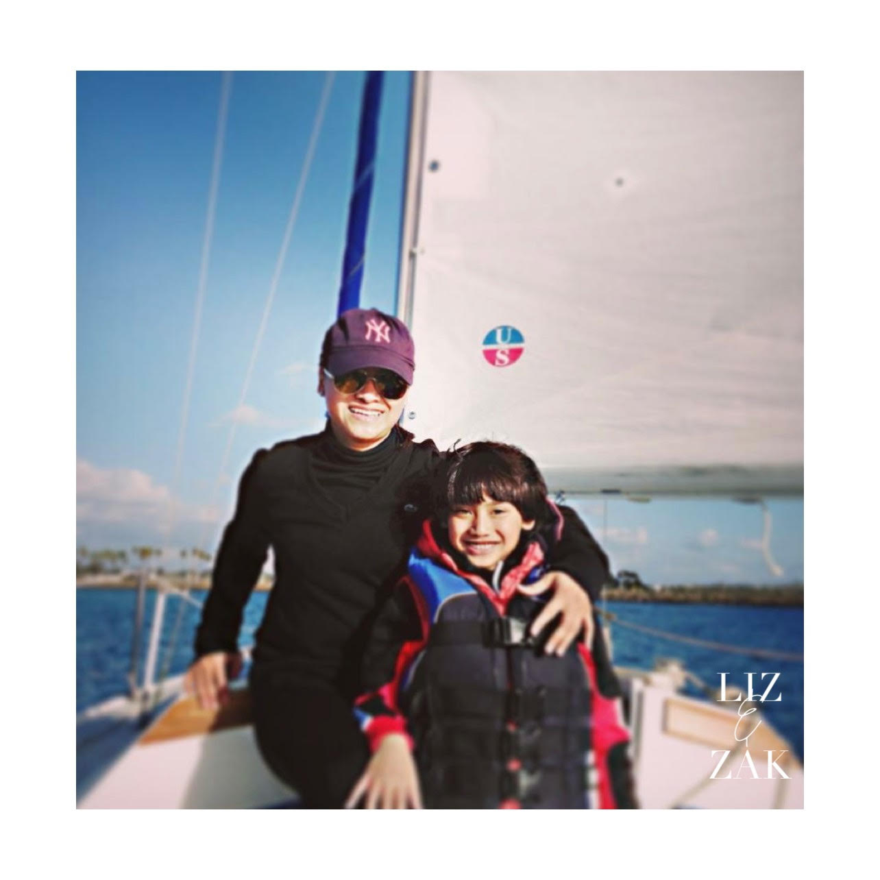 Two people on a sailboat with a clear blue sky and ocean background.